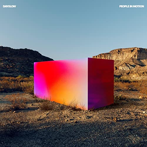 Album cover: a colorful cube in a desert landscape.