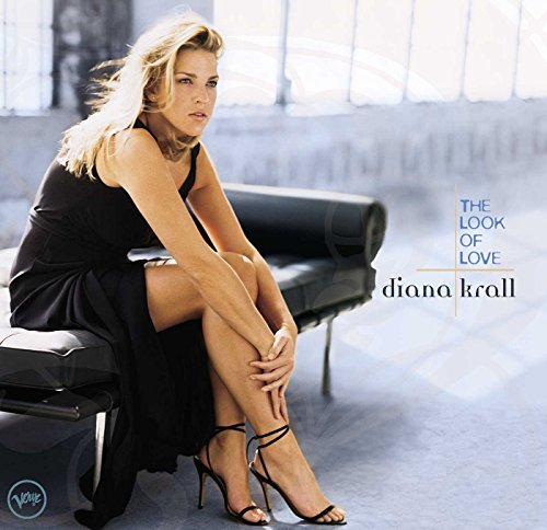 Diana Krall sits on a black bench wearing a black dress in this album cover.