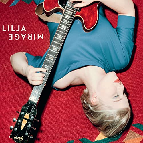 Woman with guitar lying on a red and gold patterned rug.