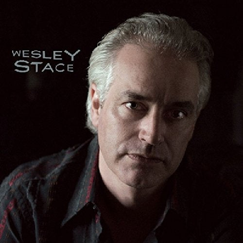 Close-up portrait of Wesley Stace, a man with graying hair, looking forward.