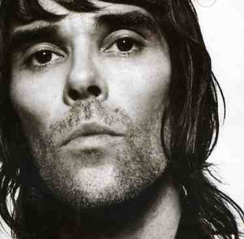 Black and white portrait of Ian Brown with dark hair and stubble.