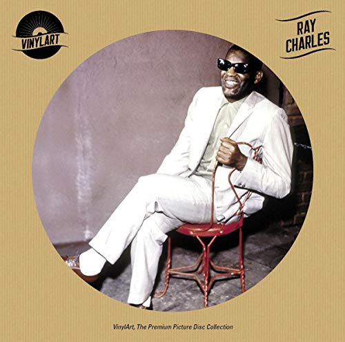 Ray Charles in a white suit, smiling, seated on a red chair.
