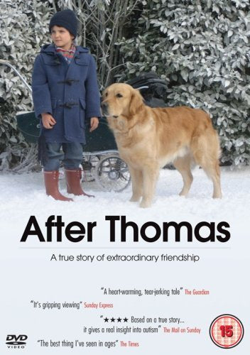 Boy in blue coat stands with golden retriever in snowy landscape.