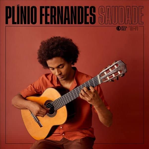 Plínio Fernandes plays an acoustic guitar against a solid terracotta-colored background.
