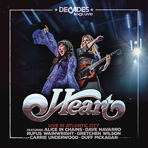 Heart band members performing live on stage with bright lights.