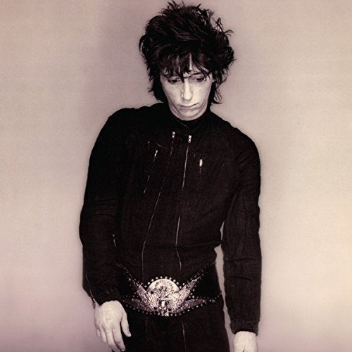 Black and white portrait of Johnny Thunders looking downward, wearing dark clothes.