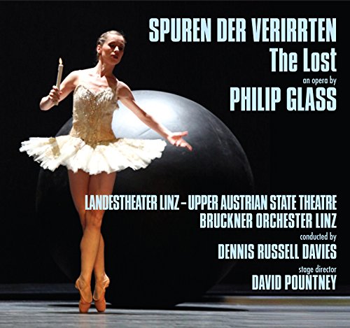 Ballerina in a tutu holds a candle before a large dark sphere.