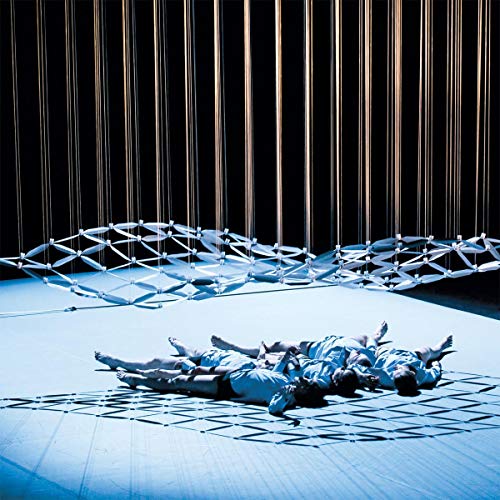 People lying on a floor with a geometric structure above them.