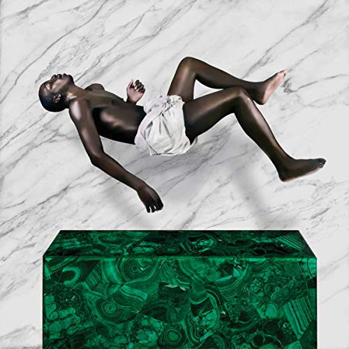 Person reclining on a green block against a marble background.