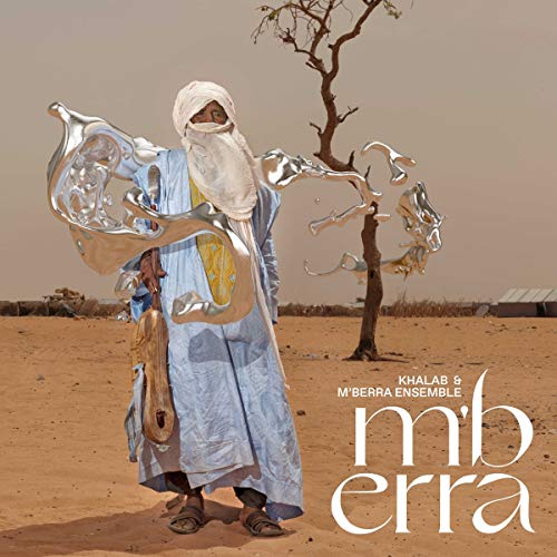 A man in traditional robes stands in a desert with floating liquid silver shapes.