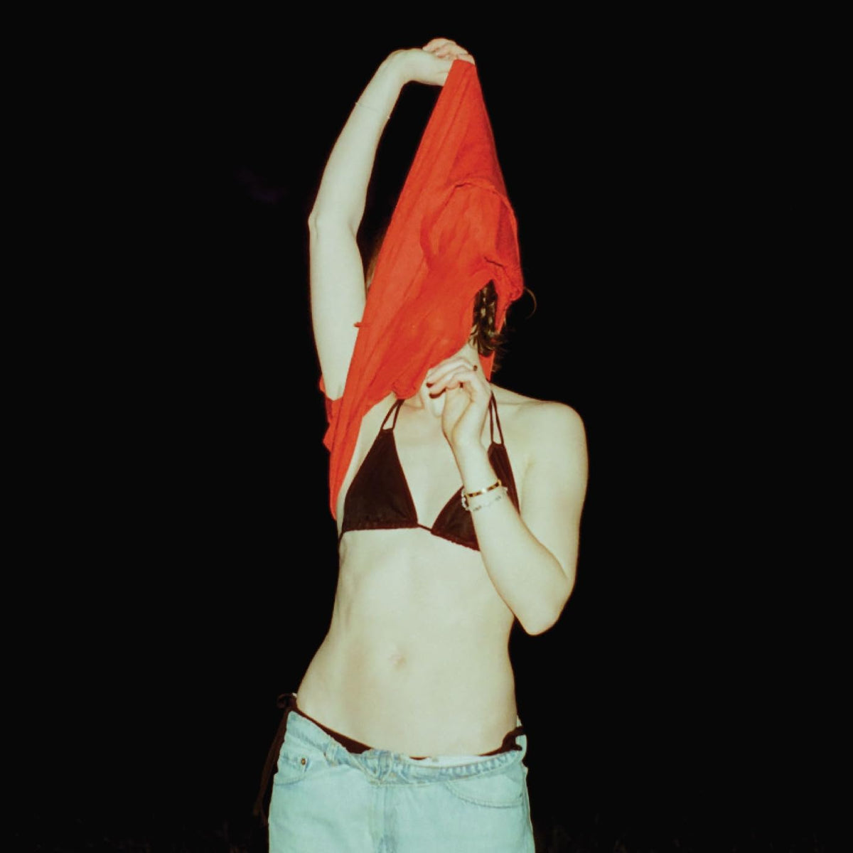 Woman in a black bikini and jeans, obscured by red fabric.