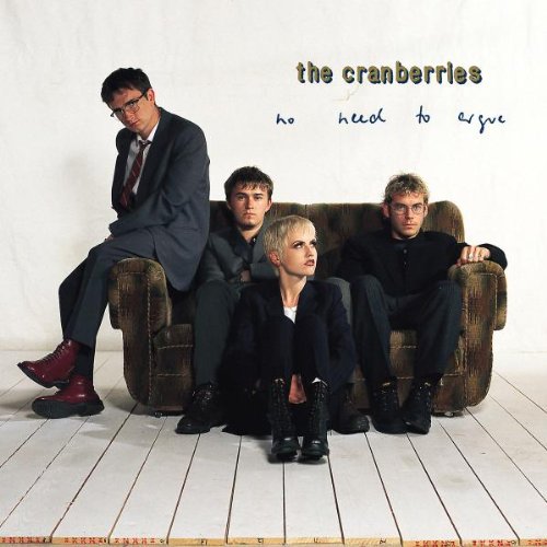 The Cranberries band members posed on a worn, brown couch.