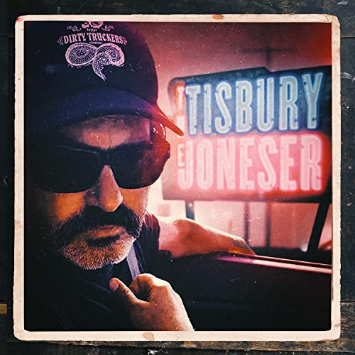 Man with mustache and sunglasses in front of neon sign.
