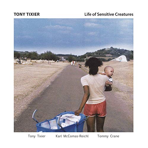 CD cover: woman carrying a baby walking down a beach road.