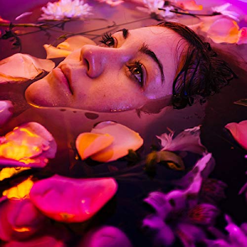 Woman’s face among pink and white rose petals in water.