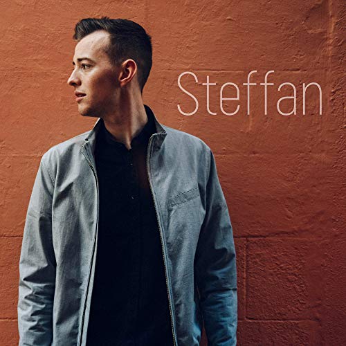 CD cover featuring a man in a jacket against a red brick wall.