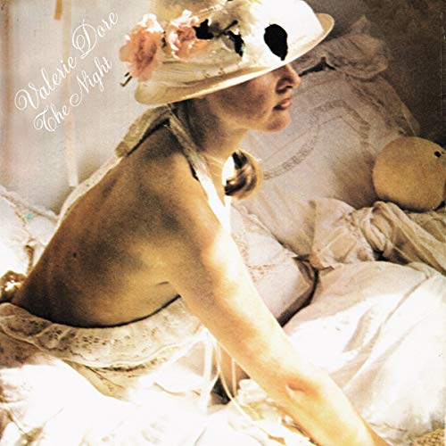 Woman in a hat reclining on white bedding, album cover art.