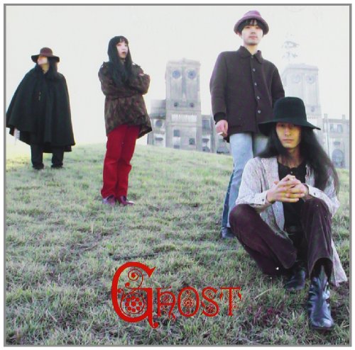 Four figures in hats and dark clothing stand in a field.