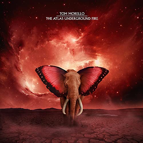 An elephant with butterfly wings stands on cracked earth under a red nebula sky.