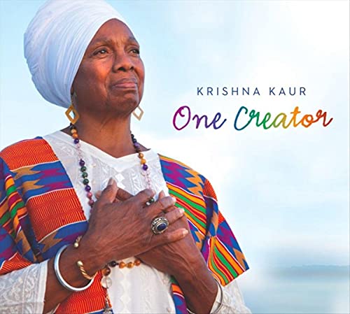 Krishna Kaur in white turban and colorful clothing, hand over heart.