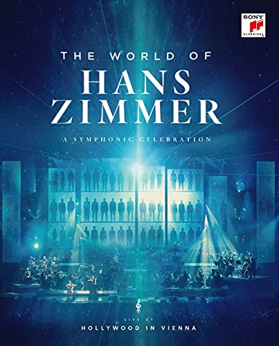 Hans Zimmer conducting an orchestra on a large stage with musicians and screens behind.
