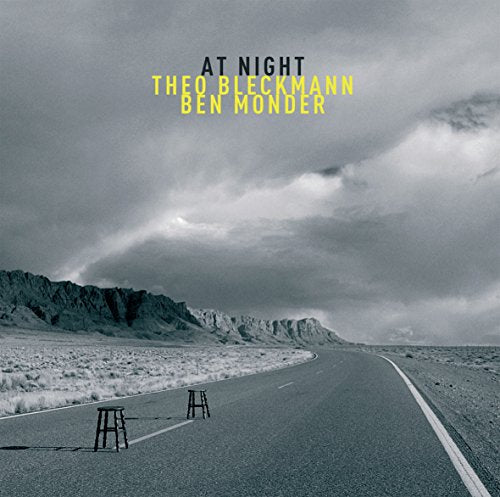 Album cover: desert landscape with a road, chairs, and text “At Night”.