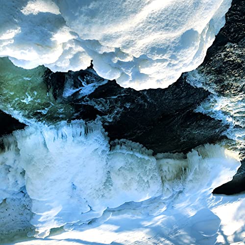 Dark water flows between thick, textured shelves of white snow and ice.