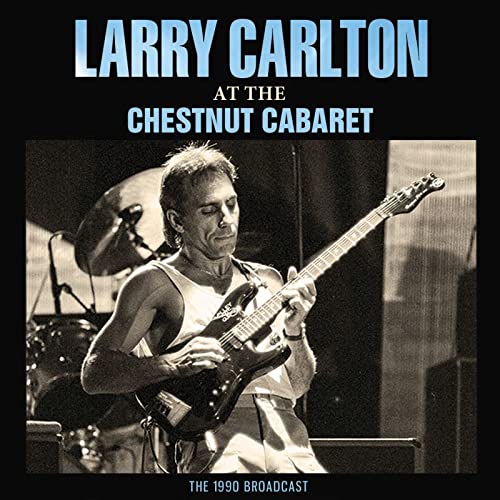 Larry Carlton playing a black electric guitar on stage, CD cover.