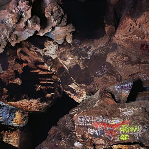 Dark, textured rock formations with faded graffiti and writing.