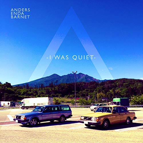 CD cover: landscape with cars, mountains, and a large white triangle.