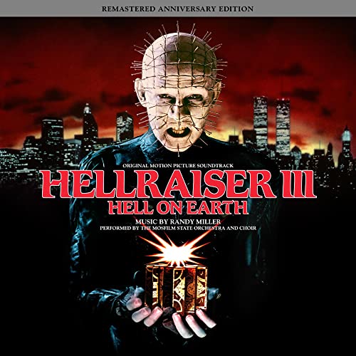 Pinhead holds a glowing puzzle box against a dark city skyline background.