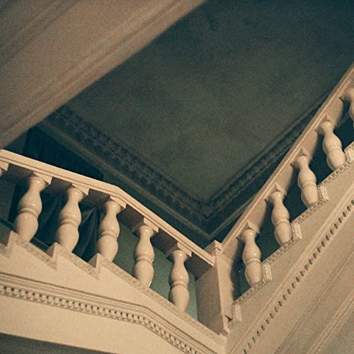 Ornate white staircase railing against a muted green wall.