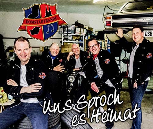 Five men in jackets pose with a motorcycle in a garage.