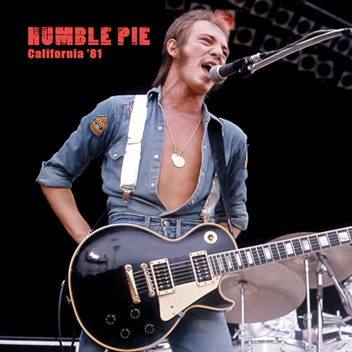 Steve Marriott singing into a microphone while playing a black electric guitar.