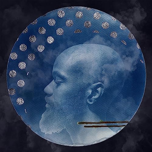 A blue-toned circular portrait of a man in profile against a cloudy background.