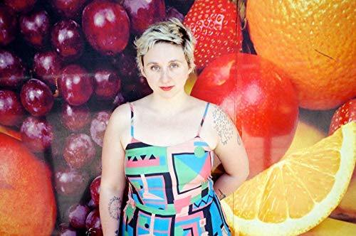 Allison Crutchfield poses in front of a colorful, oversized fruit backdrop.