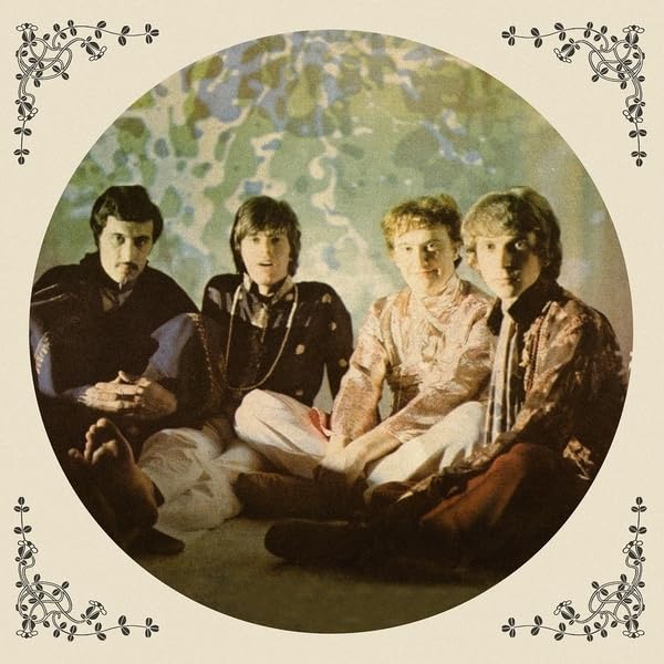 Four men in patterned clothing sit within a circular, ornate frame.