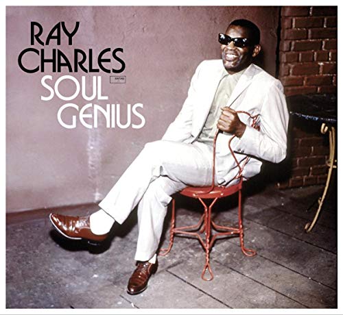 Ray Charles in a white suit sits on a red metal chair.