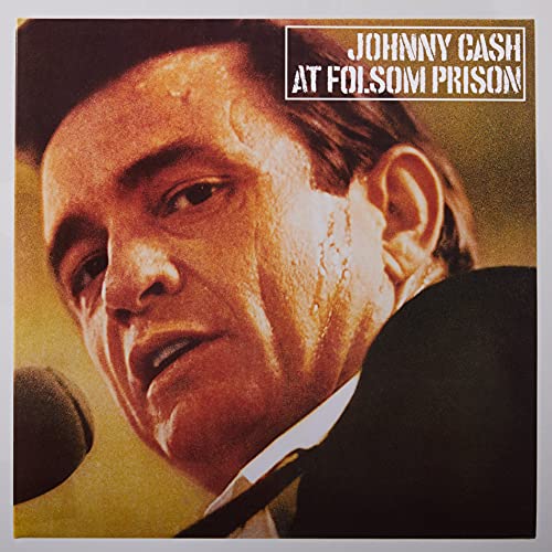 Close-up portrait of Johnny Cash singing into a microphone on a golden background.