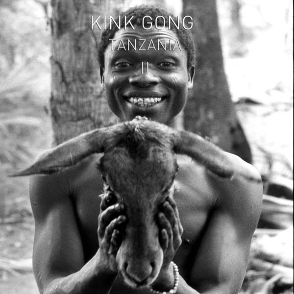 Black and white portrait of a smiling man holding a goat’s head.