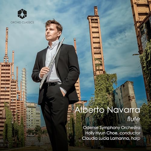 Alberto Navarra in suit holding a flute, industrial background.