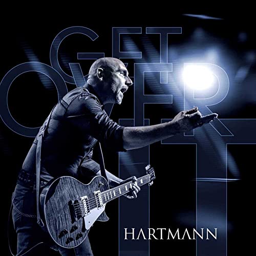 A bald man playing an electric guitar against a dark blue background with text.