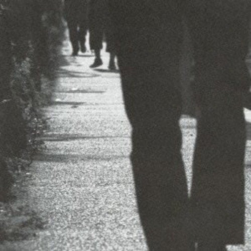 Black and white photo of figures walking down a path.