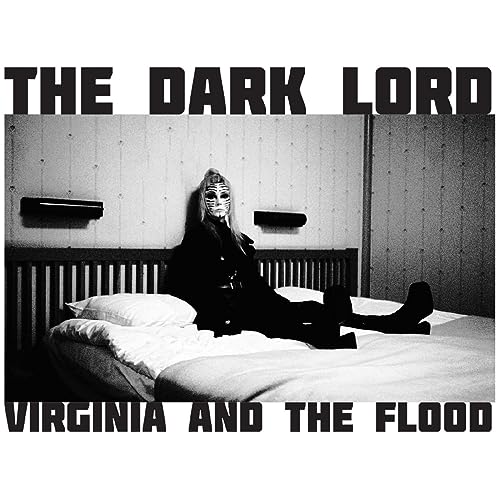 Black and white album cover featuring a person in a mask on a bed.