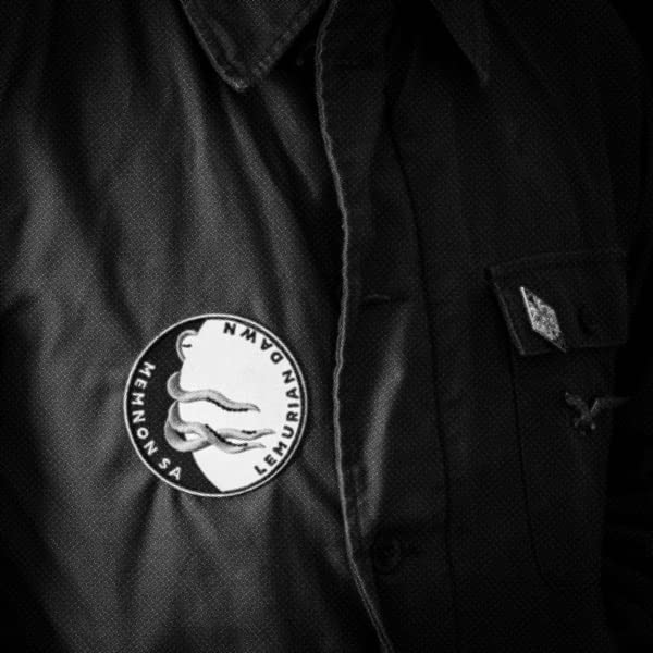 Round patch with face profile on black textured fabric.