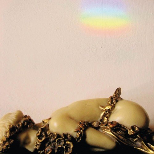Close-up of a classical sculpture with a rainbow light flare.