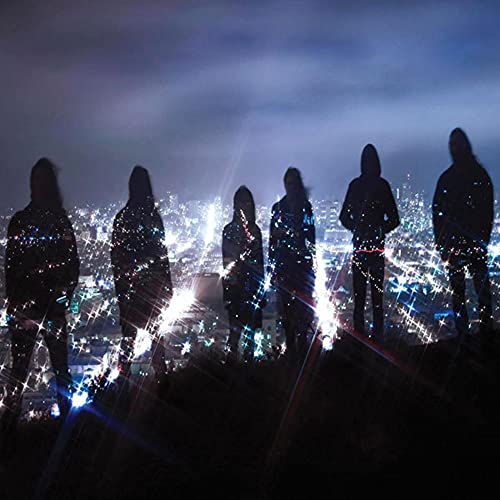 Silhouetted figures stand overlooking a glittering cityscape at night.