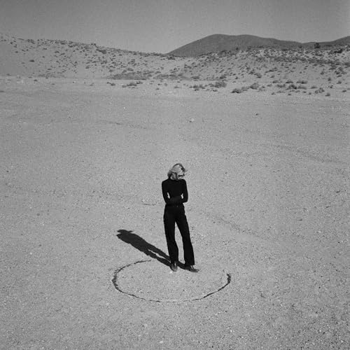 Black and white photo of a woman standing in a desert landscape.