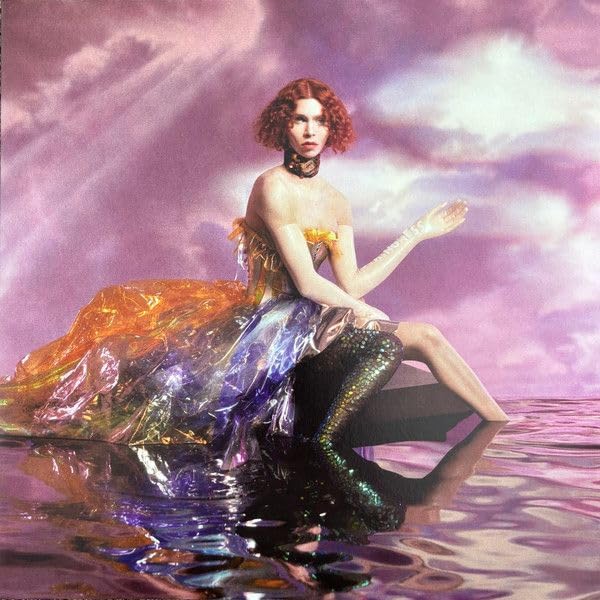 Red-haired woman in iridescent clothing sits in water against a purple sky.