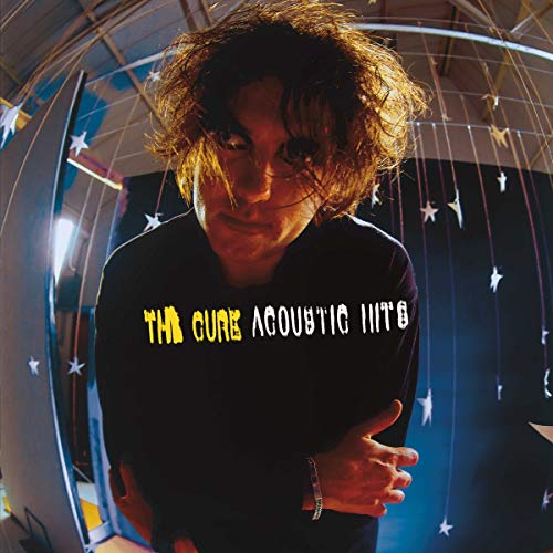 Robert Smith with messy hair against a dark background with hanging star decorations.